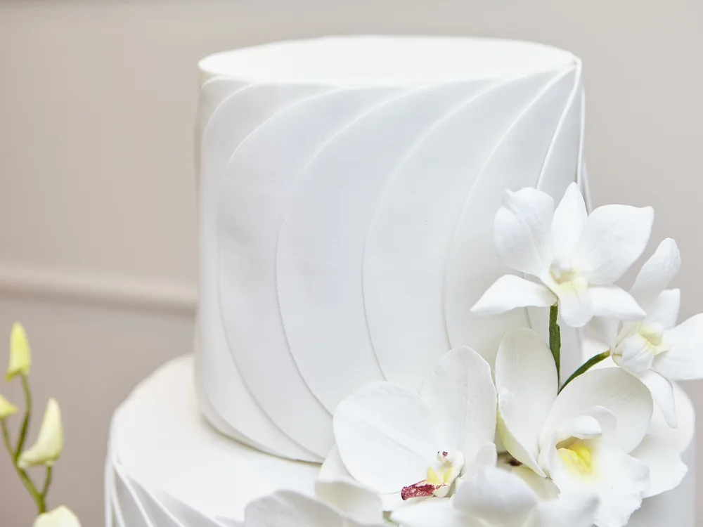 Andar superior de bolo de casamento com textura plissada e orquídeas de açúcar