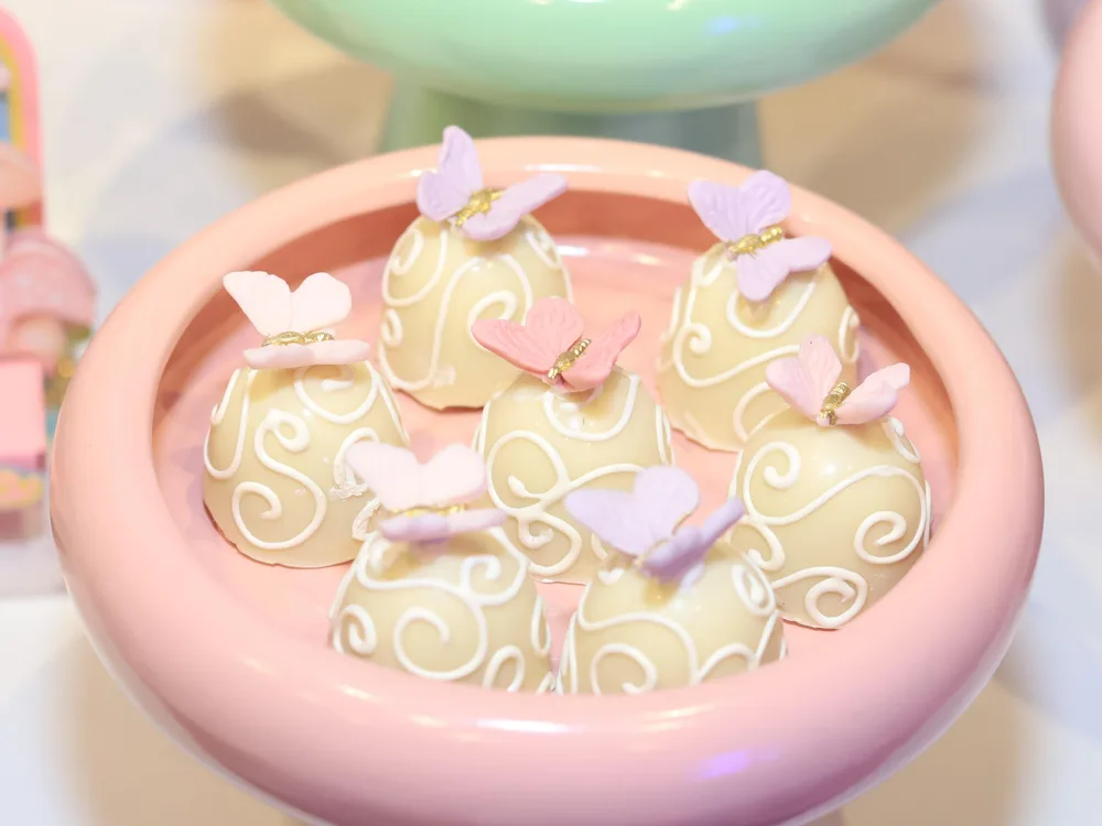 Docinhos arabescados com borboletas de açúcar em bowl rosa de festa jardim encantado
