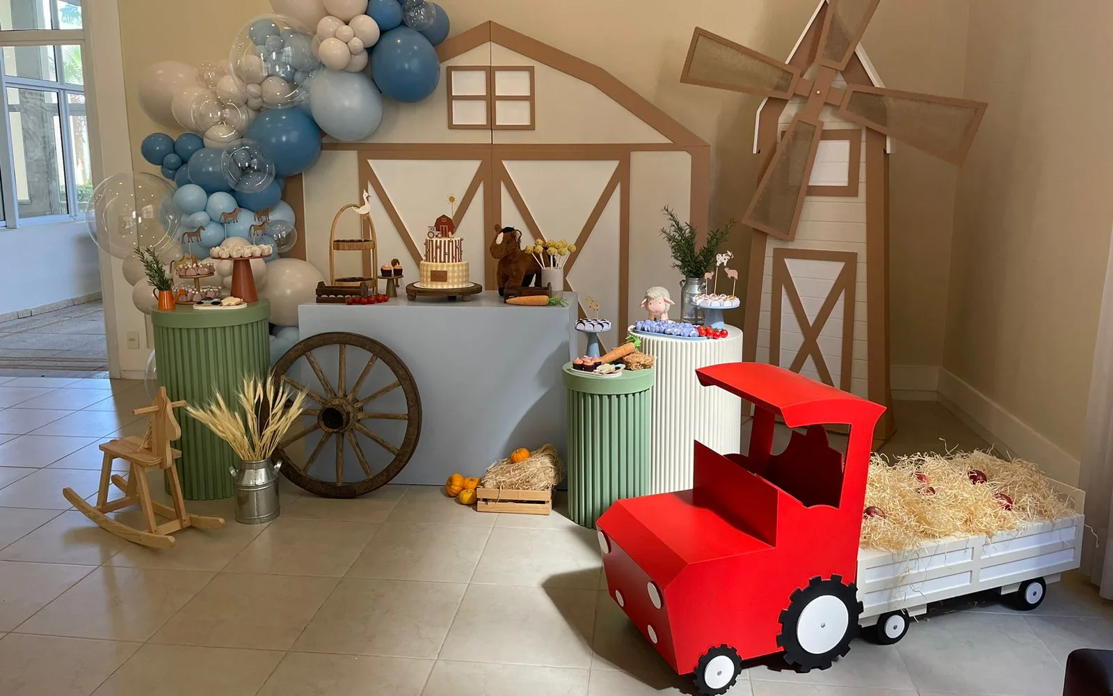 Mesa de doces tema fazendinha com celeiro, moinho e trator decorativos