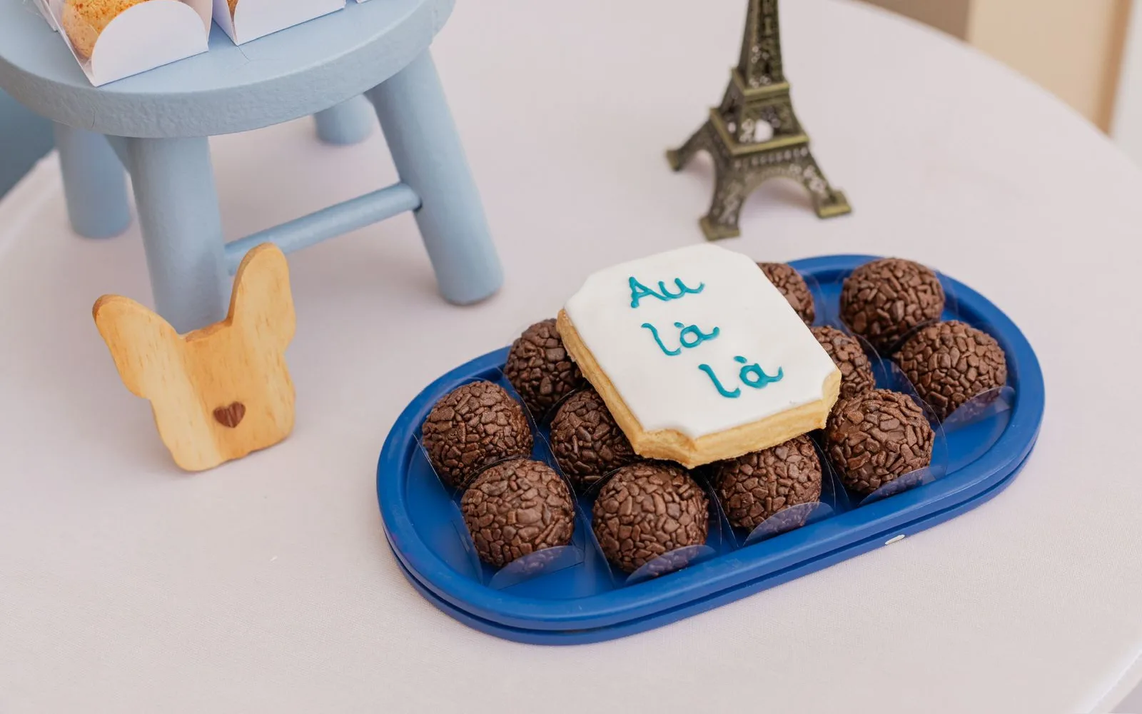 Brigadeiros e biscoito decorado em bandeja azul com mini Torre Eiffel em festa temática